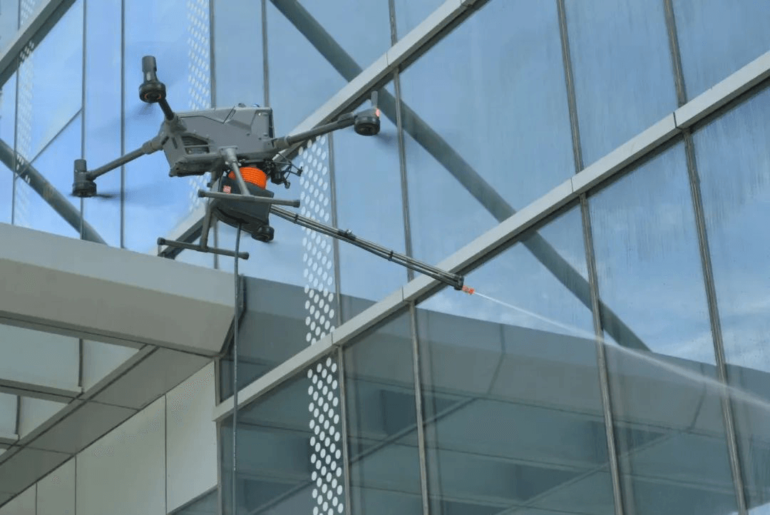 En drönare rengör fönstren på en modern byggnad med hjälp av en vattenstråle.