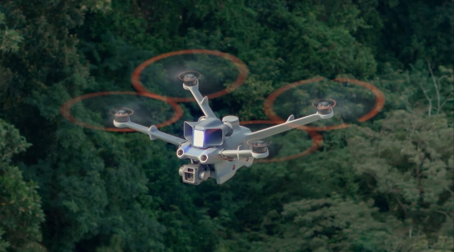 En drönare svävar över en tät skog, redo att utföra sin uppgift i det gröna landskapet.
