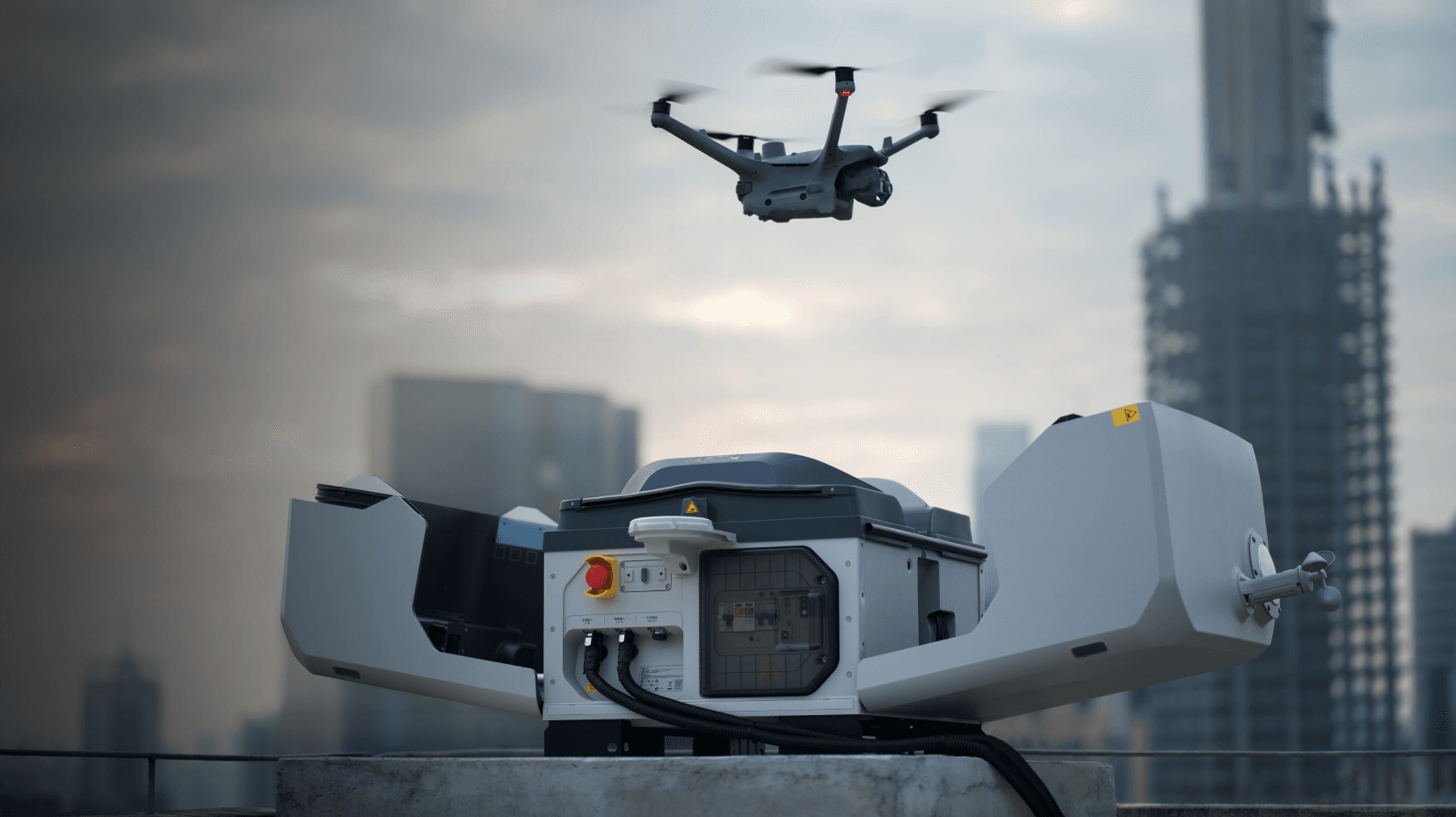 En drönare lyfter från en avancerad laddningsstation på ett tak i en stadsmiljö.