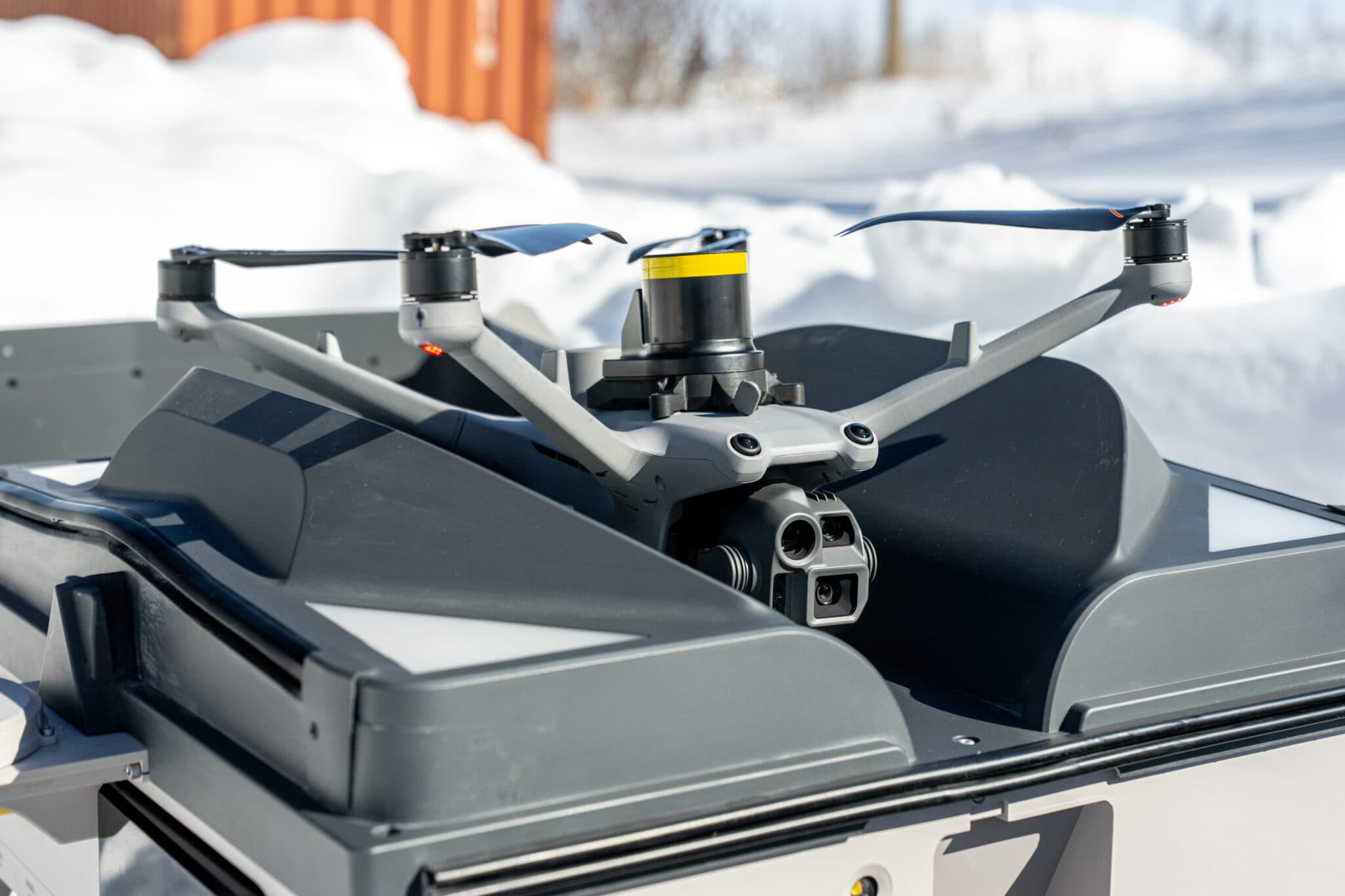 En drönare placerad på en landningsplattform i en snötäckt miljö, redo för flygning.