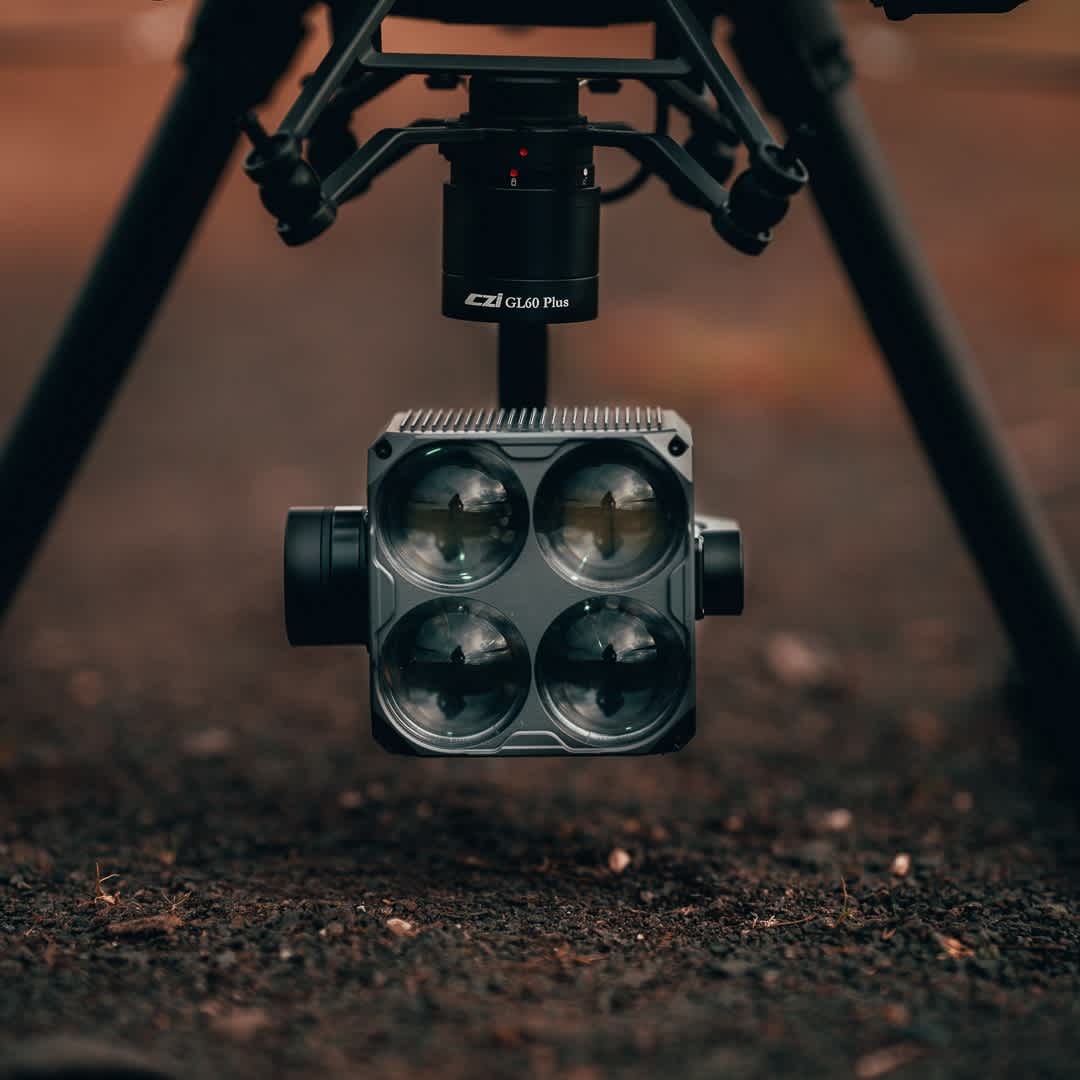 En avancerad drönare utrustad med en CZI GL60 Plus ljusenhet svävar över marken i en utomhusmiljö.