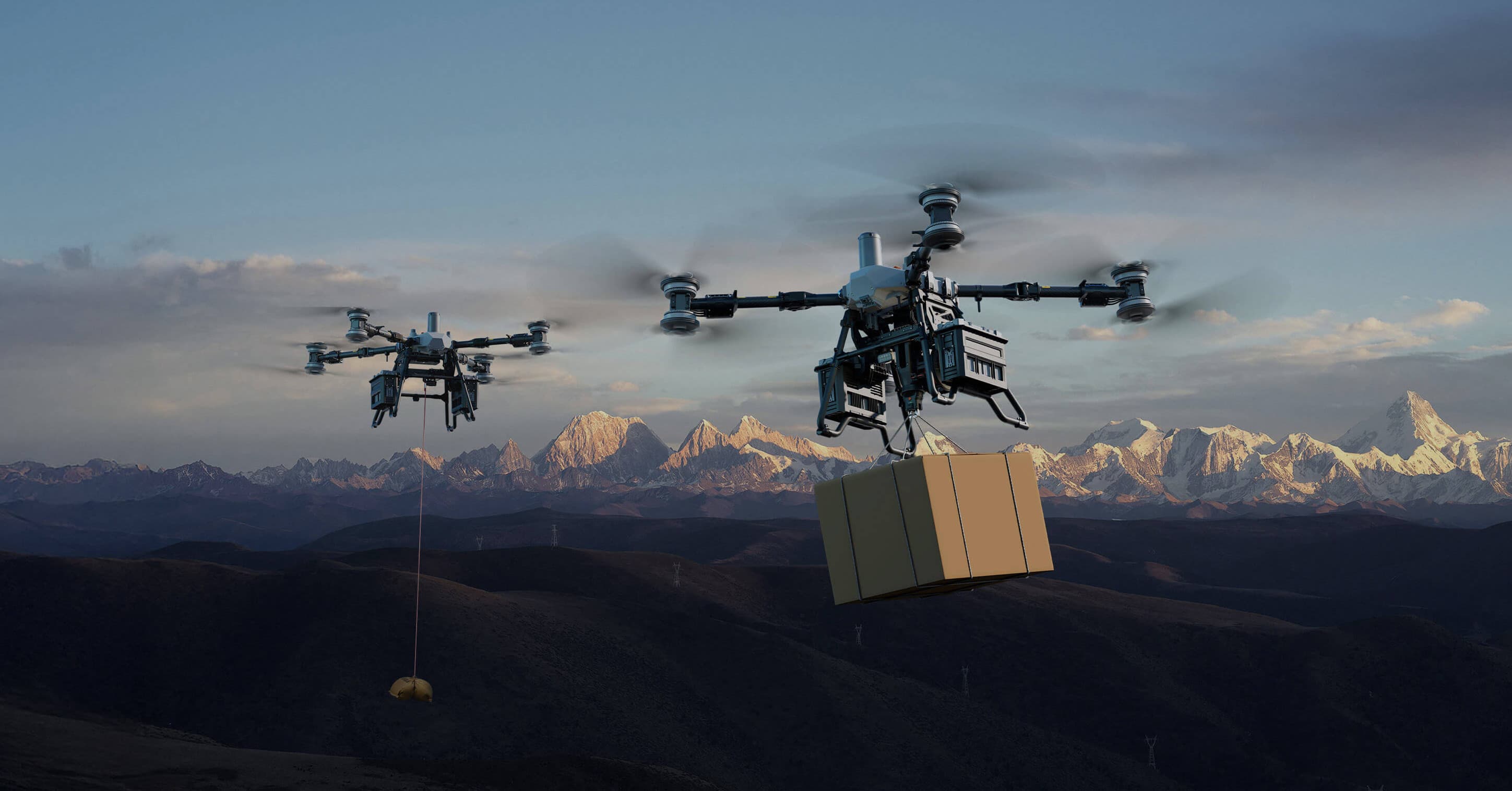 Två DJI FlyCart 100-drönare transporterar paket över ett bergigt landskap i skymningen.