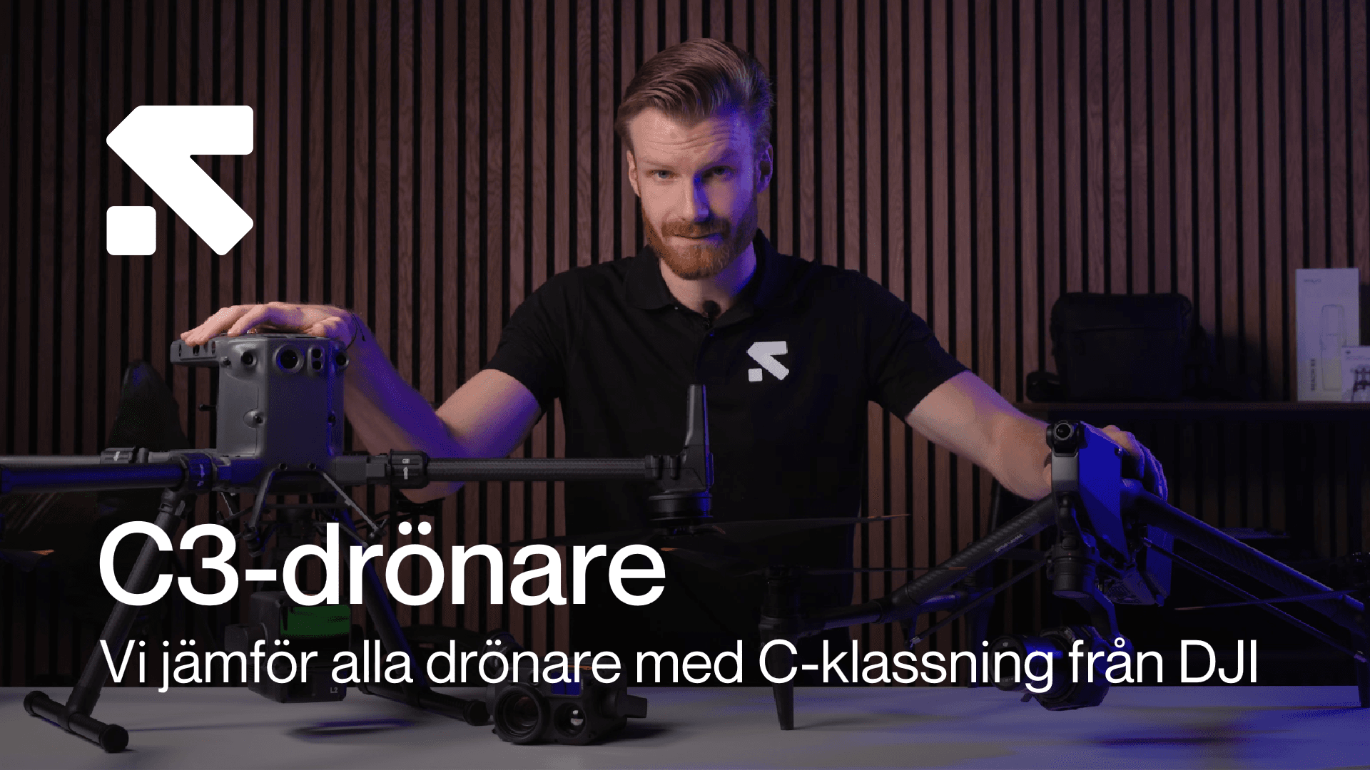 En person presenterar två stora C3-klassade drönare i en studio med träpaneler i bakgrunden, med text om jämförelse av C-klassade drönare från DJI.