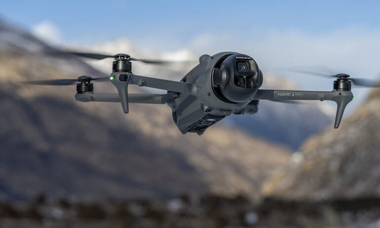 En Mavic 4 Pro svävar i luften med en bergig bakgrund, redo att fånga spektakulära vyer.