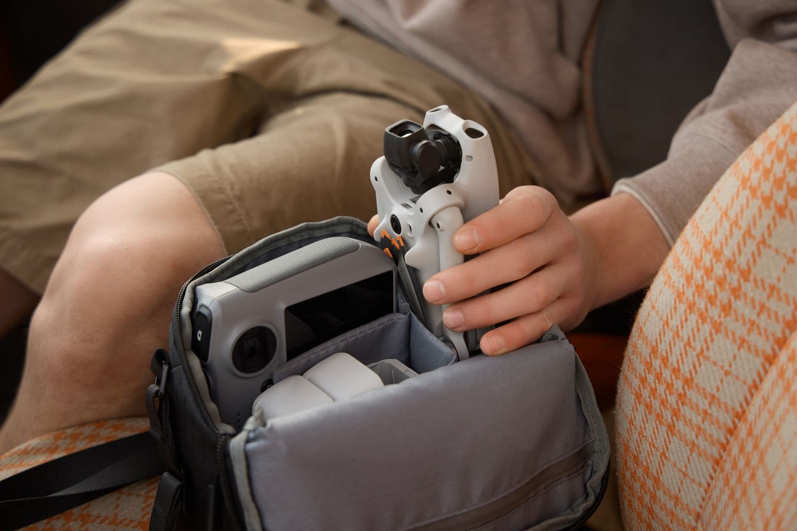 En person packar en kompakt drönare i en vadderad väska, redo för transport.