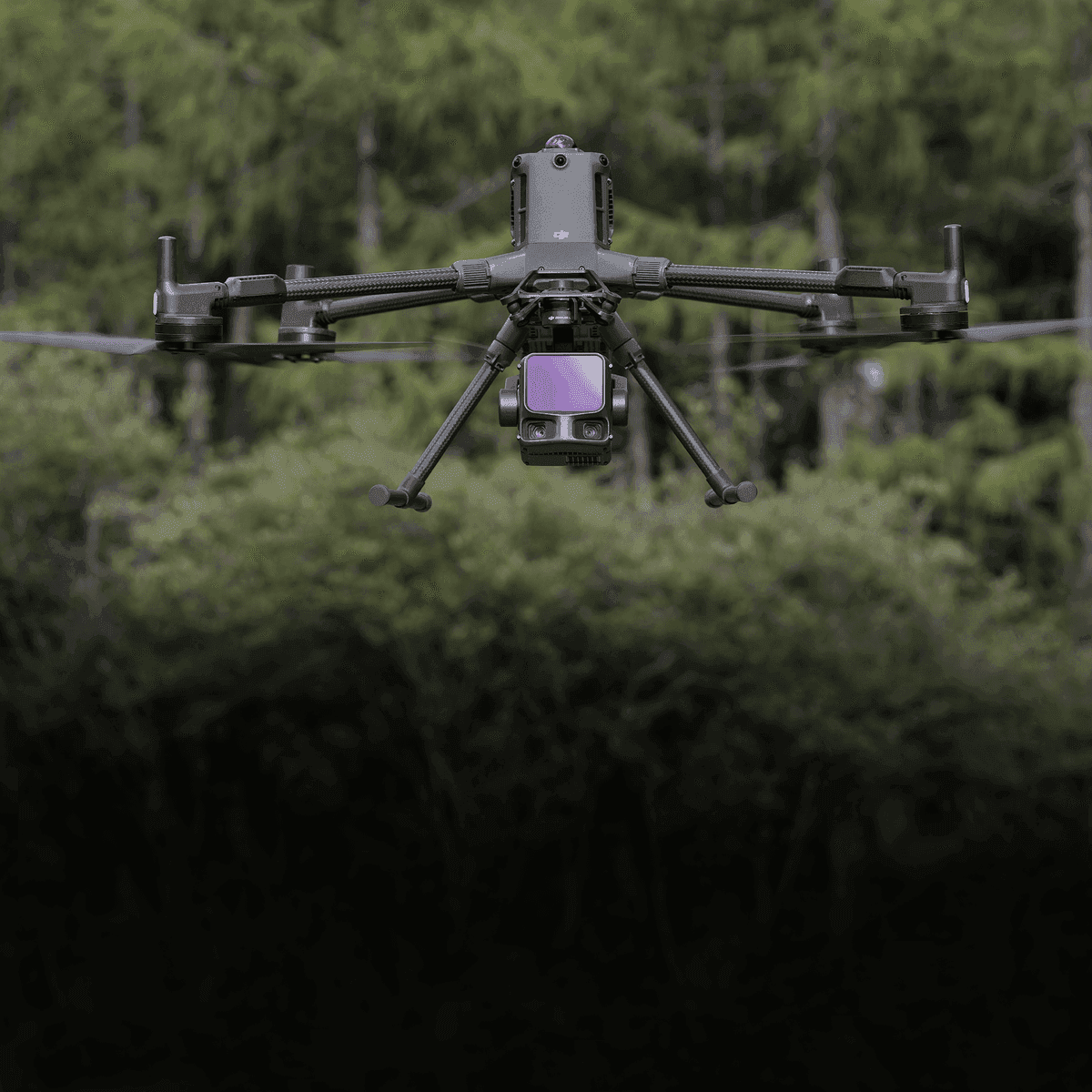 En drönare svävar framför en skog, utrustad med avancerad kamerateknik för övervakning.