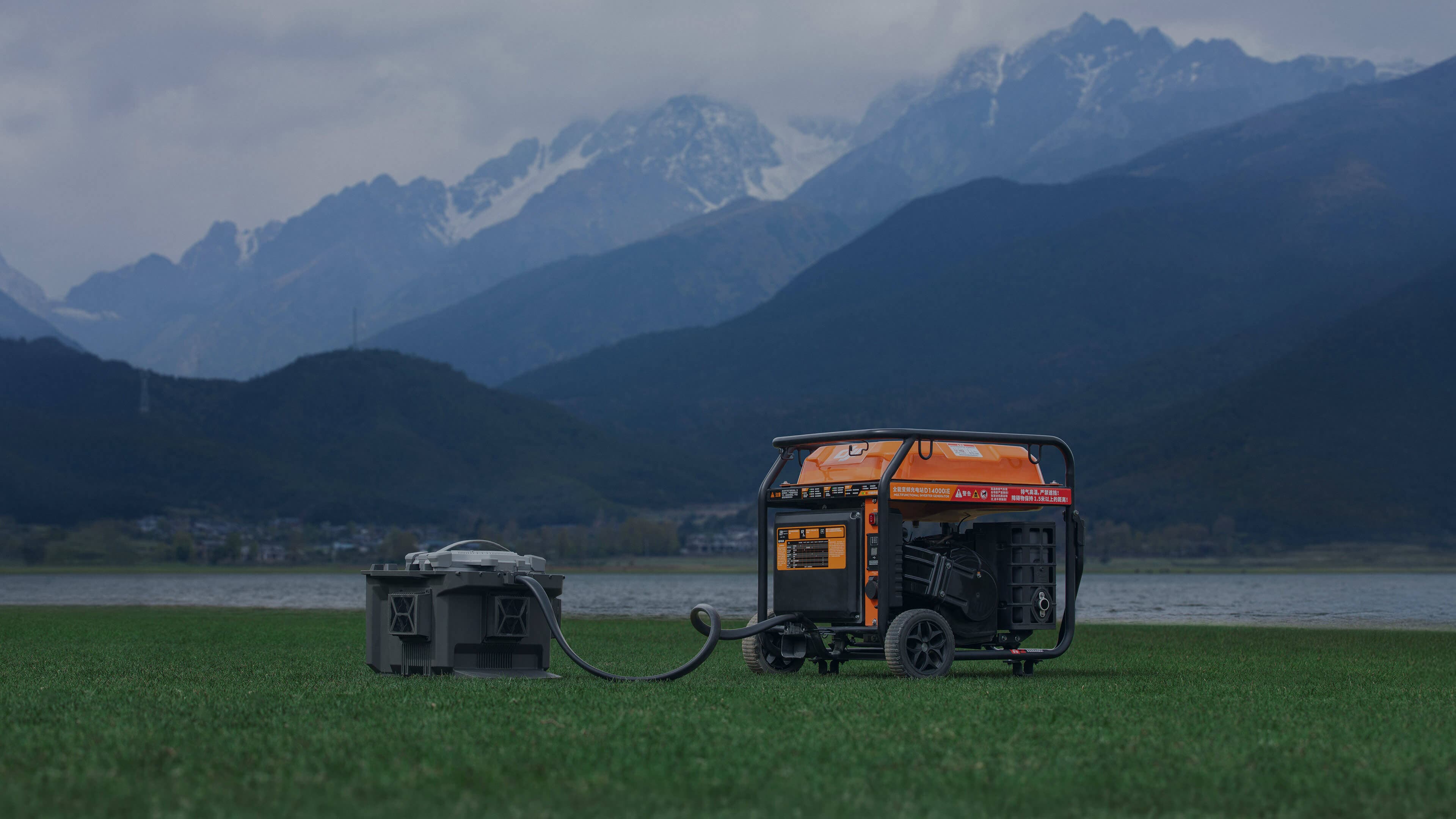 En orange generator står på en grön äng med berg i bakgrunden, ansluten till en grå enhet.