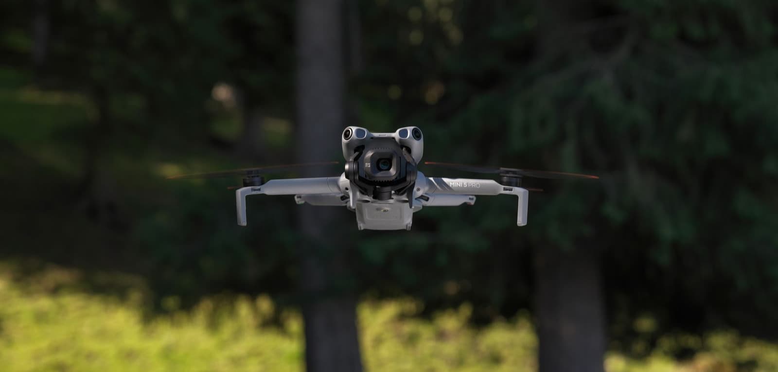 En drönare svävar i luften framför en skogsmiljö, redo för flyguppdrag.