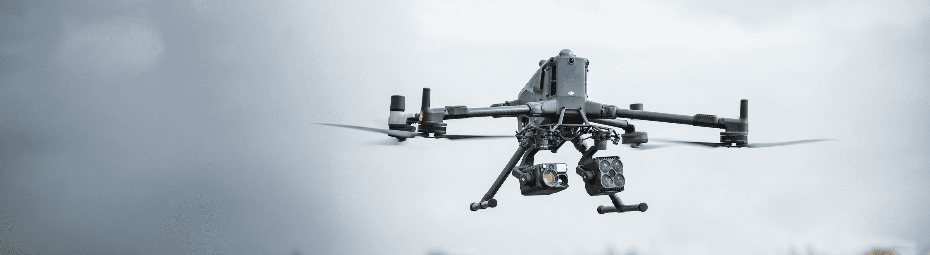 En drönare svävar över ett grönt landskap under en molnig himmel.