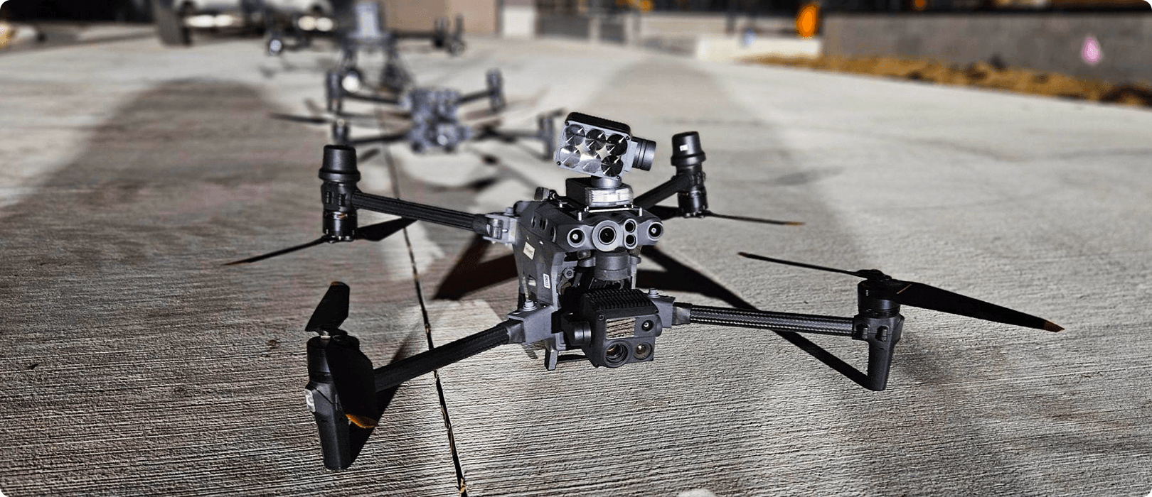 En avancerad DJI-drönare med flera sensorer från CZI står på en betongyta, redo för uppdrag i en urban miljö.