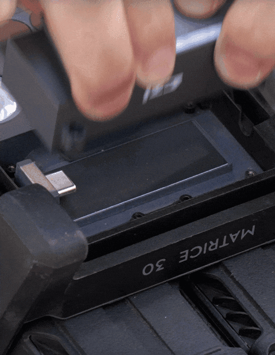 En person installerar ett batteri i en teknisk enhet märkt 'Matrice 30', vilket tyder på en drönarinstallation.