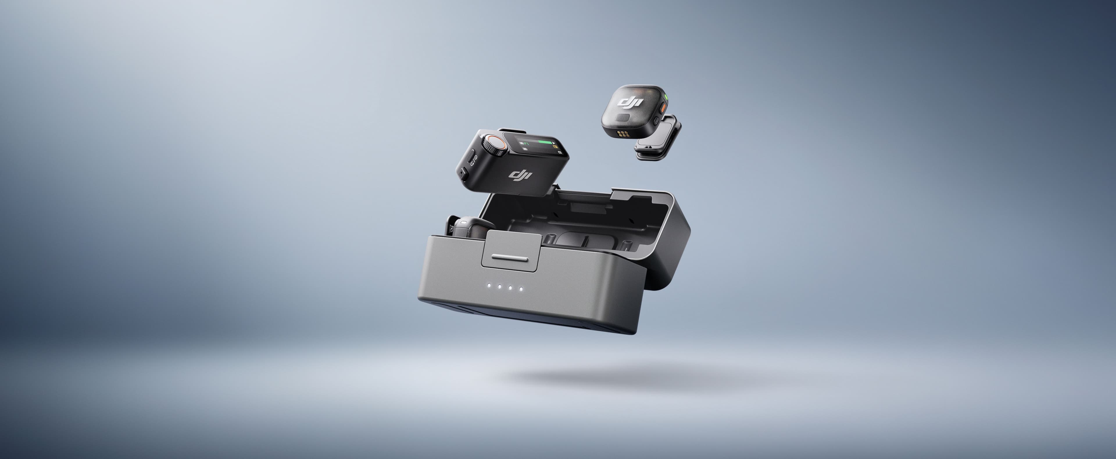 Två små elektroniska enheter svävar ovanför en öppen laddningsstation mot en mjukt belyst bakgrund.