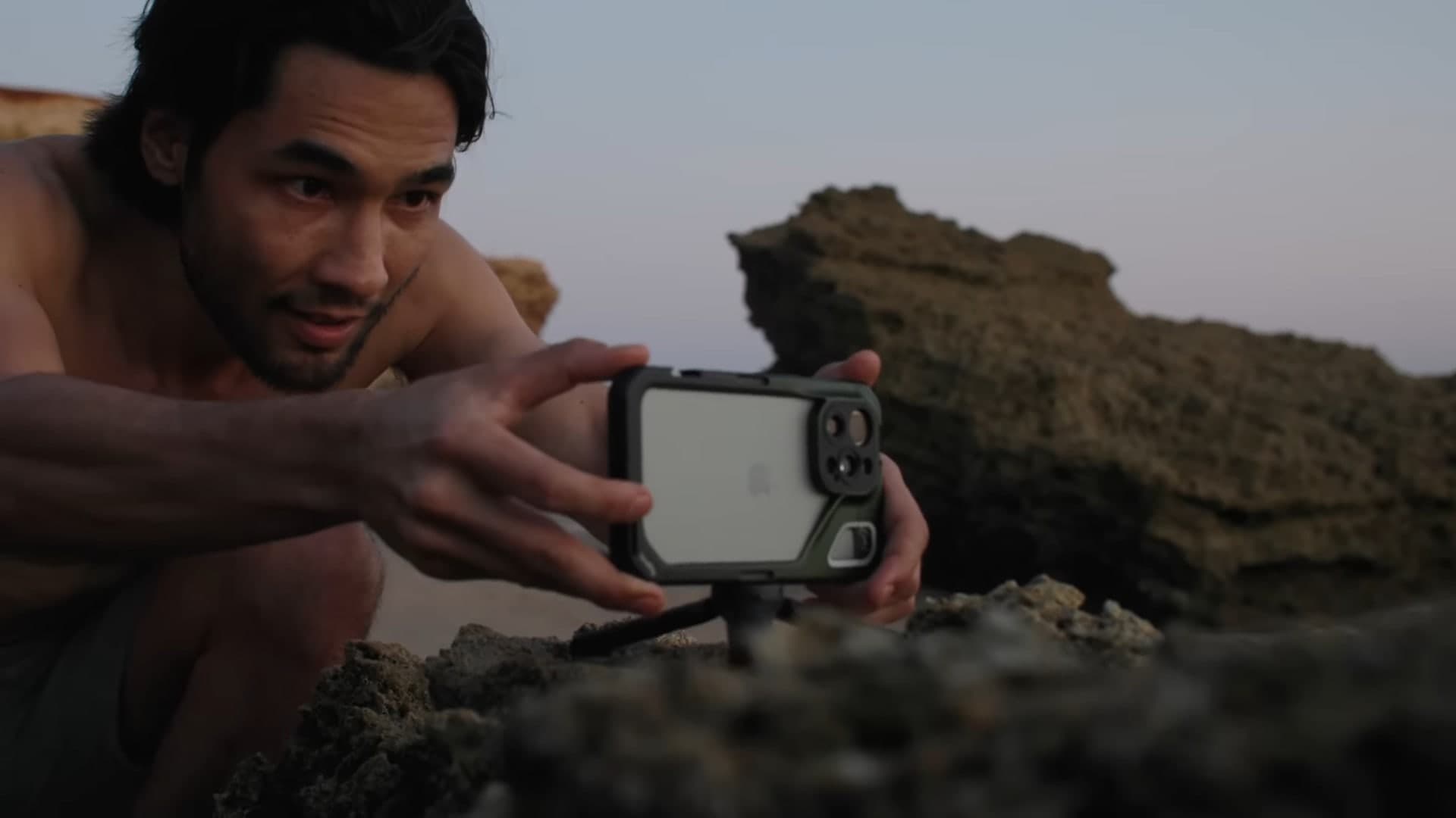 Filmaren Brandon Li ställer en iPhone i SmallRig-bur på ett litet stativ bland klipporna i skymningen.